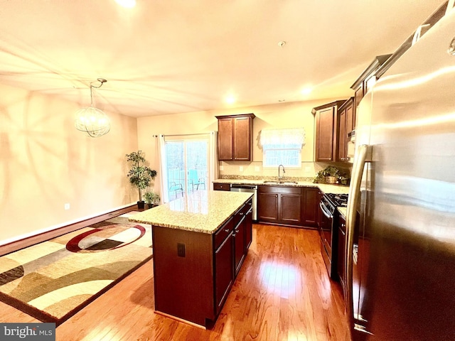 kitchen featuring a sink, a kitchen island, appliances with stainless steel finishes, and hardwood / wood-style flooring