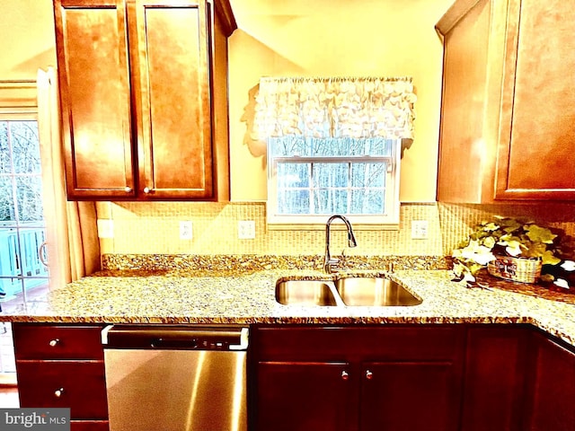 kitchen featuring stainless steel dishwasher, decorative backsplash, light stone countertops, and a sink