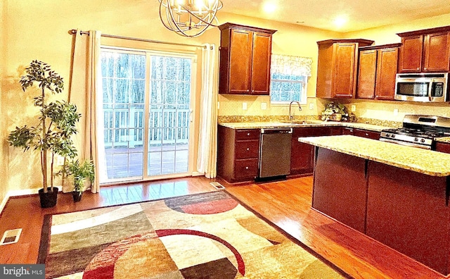 kitchen with visible vents, light stone countertops, light wood-style flooring, stainless steel appliances, and a sink