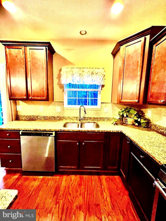 kitchen featuring a sink, light stone countertops, stainless steel dishwasher, and wood finished floors