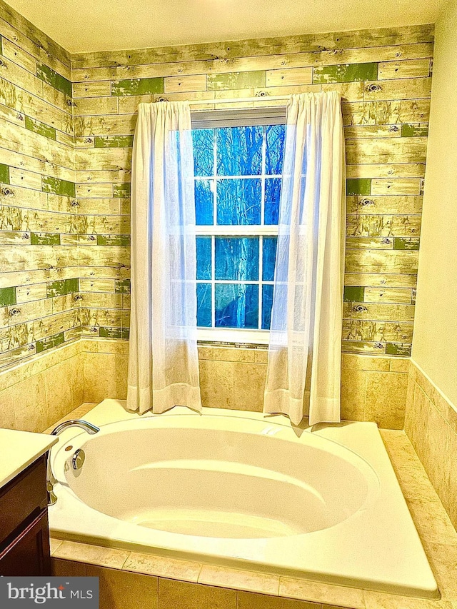 bathroom featuring a garden tub, wood walls, and vanity