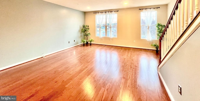 unfurnished room with stairs, baseboards, and wood finished floors