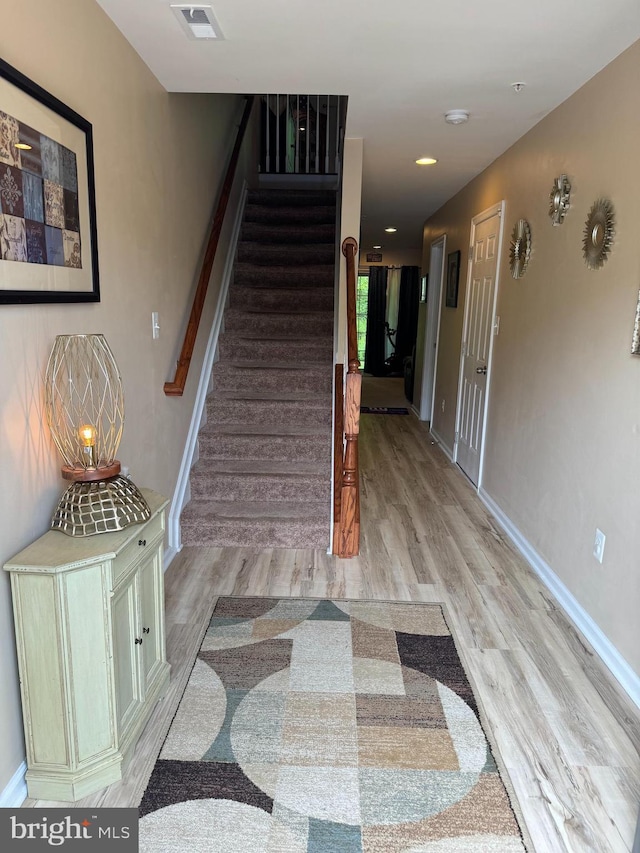 staircase featuring wood finished floors, visible vents, and baseboards