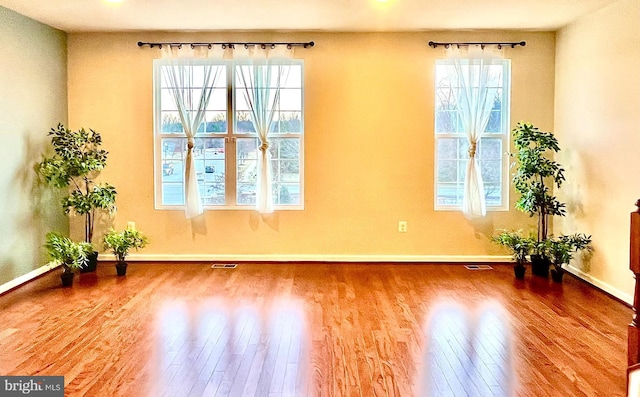 empty room featuring visible vents, baseboards, and hardwood / wood-style floors