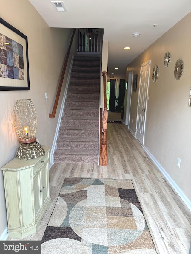 stairs featuring visible vents, baseboards, and wood finished floors