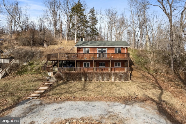 view of front facade featuring a chimney, faux log siding, and a wooden deck