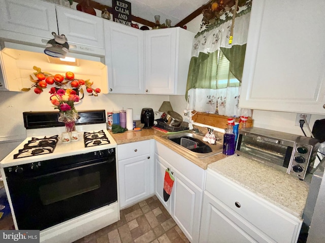 kitchen with a sink, light countertops, range with gas cooktop, and white cabinetry