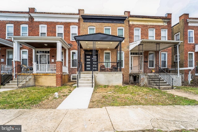 townhome / multi-family property with brick siding and a porch