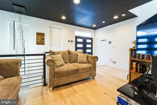 living area with recessed lighting, visible vents, light wood-style flooring, and baseboards