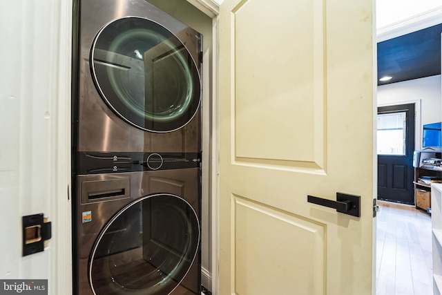 washroom with wood finished floors, laundry area, and stacked washing maching and dryer