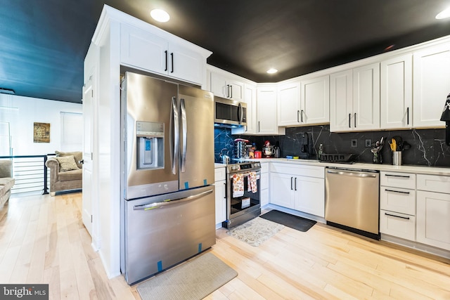 kitchen featuring appliances with stainless steel finishes, white cabinets, and light wood finished floors