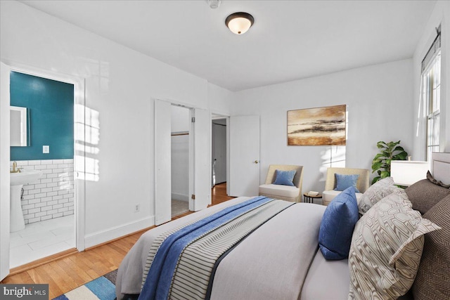 bedroom with connected bathroom and wood finished floors