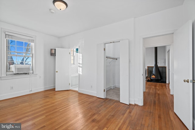 unfurnished bedroom featuring a spacious closet, a closet, light wood-type flooring, and baseboards