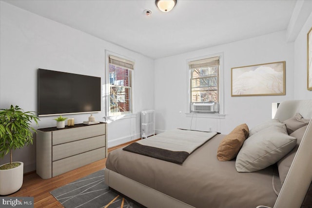 bedroom with cooling unit, wood finished floors, and radiator