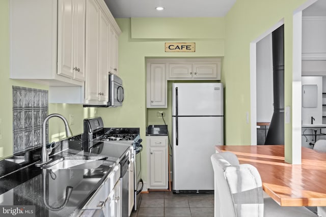 kitchen with dark tile patterned flooring, appliances with stainless steel finishes, dark countertops, and a sink