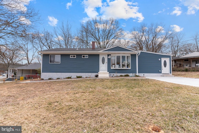 view of front of house with entry steps, a chimney, concrete driveway, and a front yard