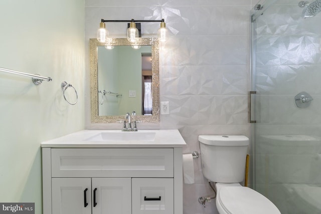 bathroom featuring toilet, a tile shower, tile walls, and vanity