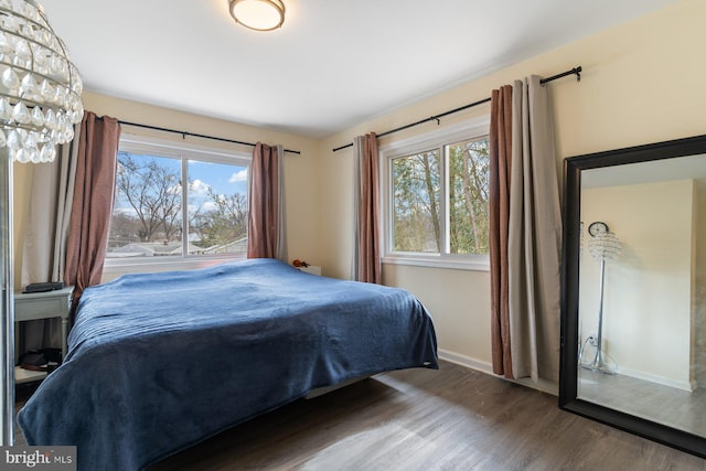 bedroom featuring a notable chandelier, baseboards, and wood finished floors