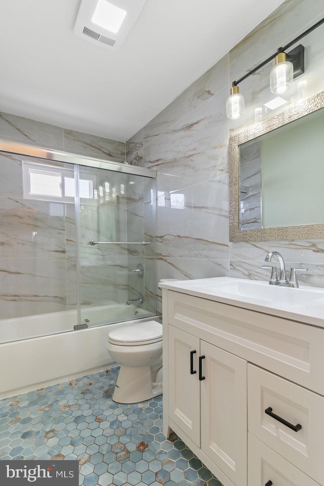 full bath with shower / bath combination with glass door, tile walls, visible vents, toilet, and vanity