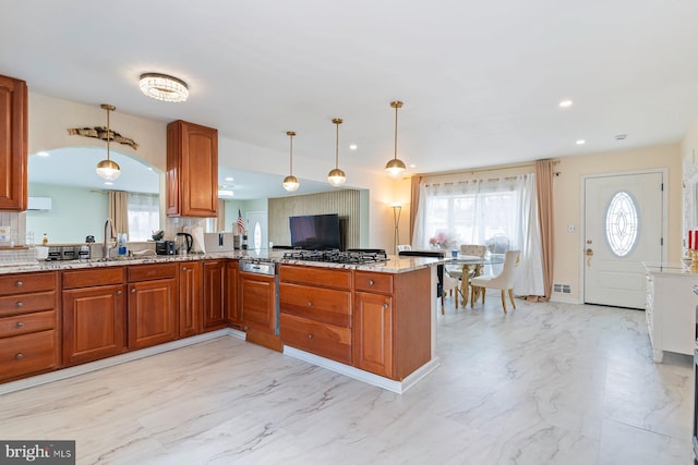 kitchen with marble finish floor, brown cabinets, recessed lighting, light stone countertops, and a peninsula