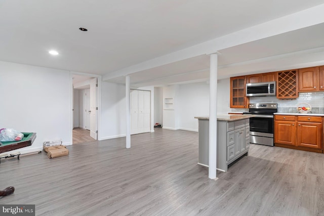 kitchen featuring light wood-style floors, stainless steel appliances, light countertops, and open floor plan