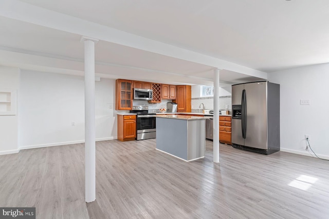 kitchen featuring a kitchen island, light countertops, appliances with stainless steel finishes, backsplash, and light wood finished floors