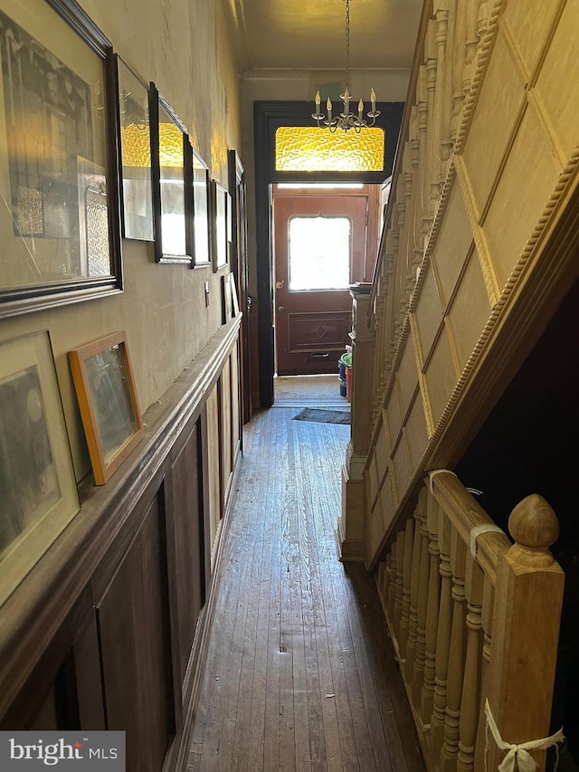 corridor featuring dark wood-type flooring, stairway, and a chandelier