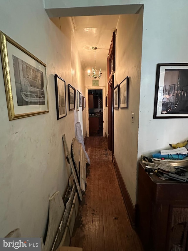 corridor featuring a notable chandelier, baseboards, and hardwood / wood-style flooring