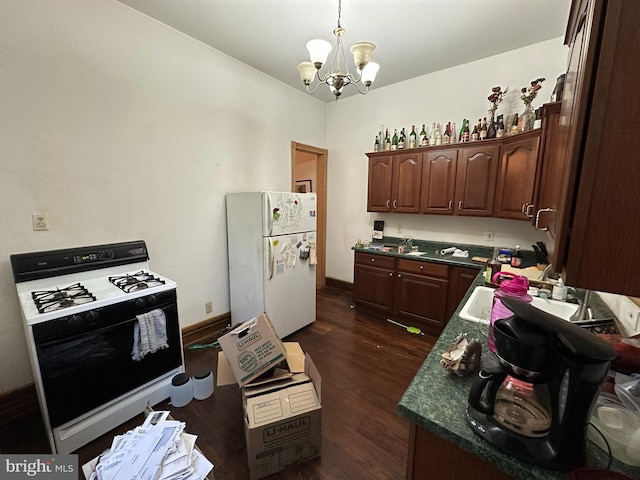 kitchen with dark countertops, freestanding refrigerator, range with gas cooktop, an inviting chandelier, and dark wood-style flooring