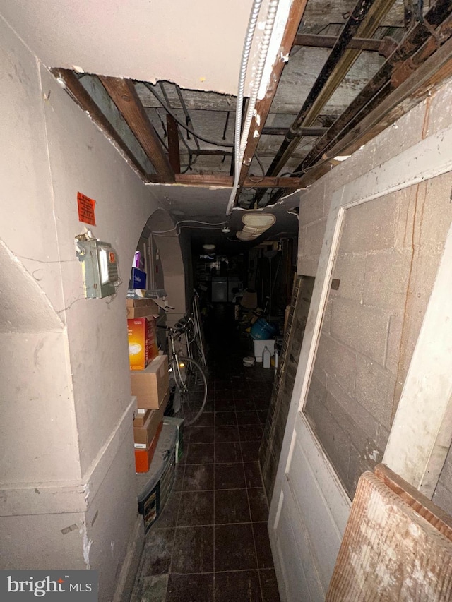 hall featuring tile patterned flooring and concrete block wall