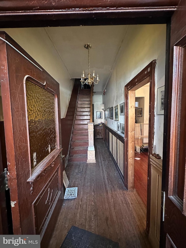 hall featuring visible vents, an inviting chandelier, dark wood-style floors, and stairs