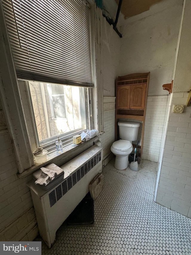 bathroom featuring toilet, tile walls, radiator, and wainscoting