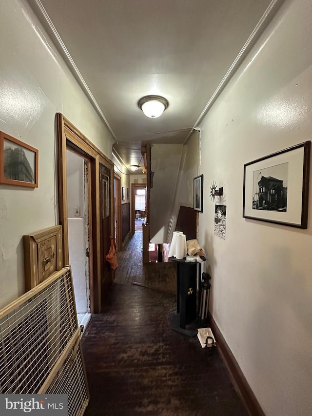 hall with crown molding, baseboards, and wood finished floors