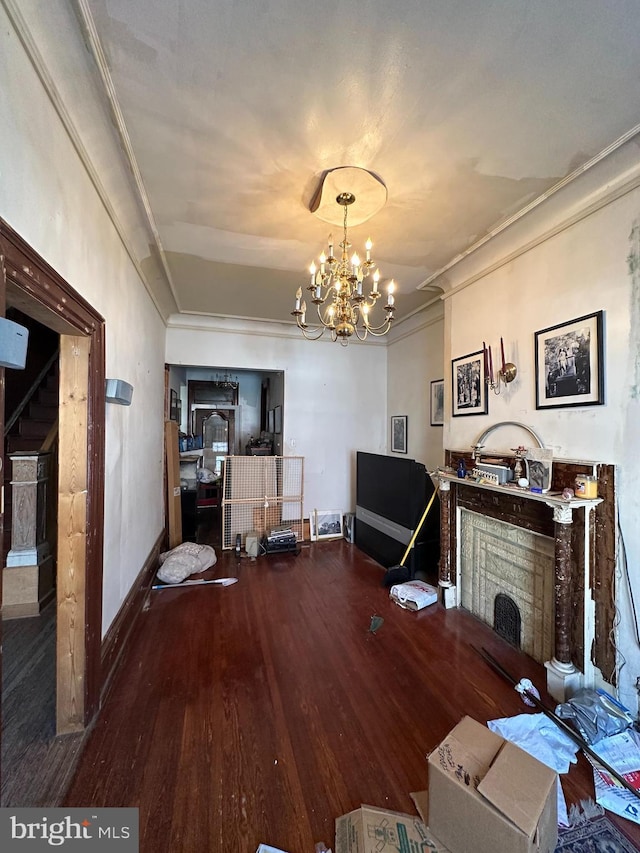 unfurnished living room with a notable chandelier, wood finished floors, baseboards, and ornamental molding