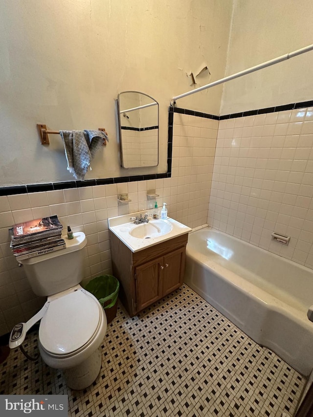 bathroom featuring tile walls, toilet, shower / bath combination, wainscoting, and vanity