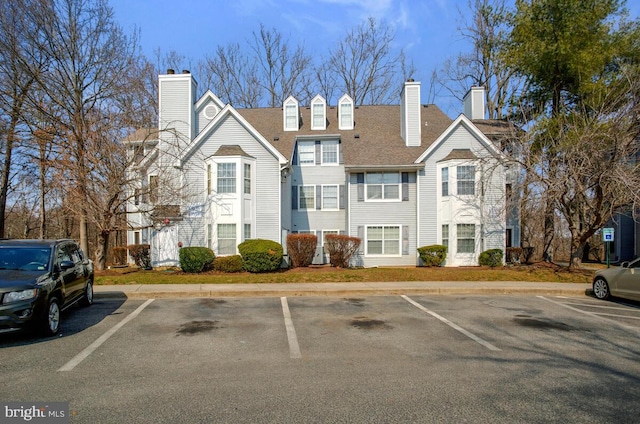 view of front of property featuring a chimney and uncovered parking