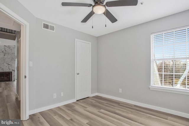 unfurnished bedroom with baseboards, visible vents, ceiling fan, wood finished floors, and a fireplace