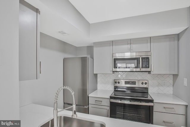 kitchen featuring a sink, gray cabinets, stainless steel appliances, and light countertops