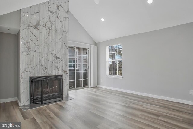 unfurnished living room featuring a high end fireplace, baseboards, and wood finished floors