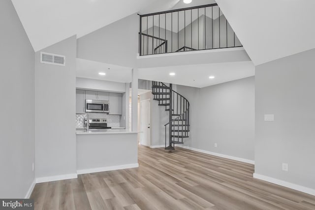 unfurnished living room featuring visible vents, baseboards, and wood finished floors