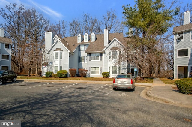 view of front of house with uncovered parking, a chimney, and a residential view