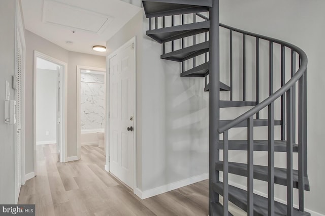 staircase featuring wood finished floors and baseboards