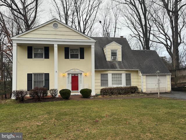 neoclassical home featuring an attached garage, driveway, and a front yard