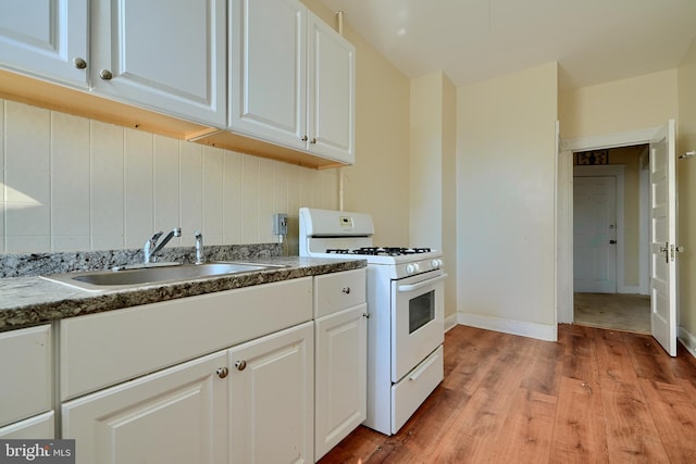 kitchen with white cabinets, white range with gas cooktop, tasteful backsplash, and a sink