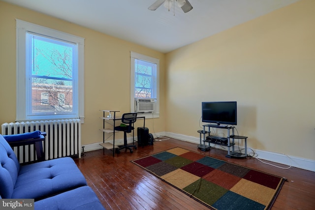 living area with radiator, ceiling fan, cooling unit, baseboards, and hardwood / wood-style flooring