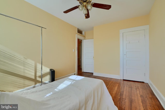 bedroom featuring hardwood / wood-style flooring, ceiling fan, baseboards, and a closet