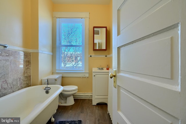 bathroom featuring a freestanding tub, vanity, toilet, and wood finished floors