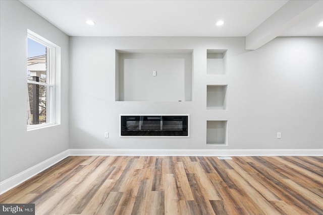 unfurnished living room featuring recessed lighting, wood finished floors, baseboards, heating unit, and a glass covered fireplace