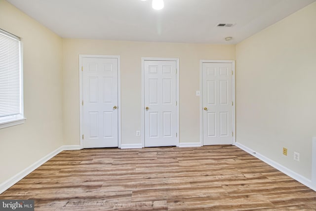 unfurnished bedroom with baseboards, visible vents, and wood finished floors