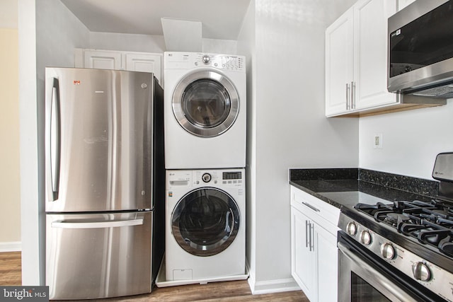 laundry area with stacked washer and dryer, laundry area, baseboards, and wood finished floors